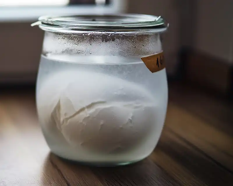 Recettes Burratas Créatives & Fromages Frais 26 Entree italienne burrata cremeuse servie sur assiette blanche a table avec couverts en argent verres de vin blanc et nappe en lin 1